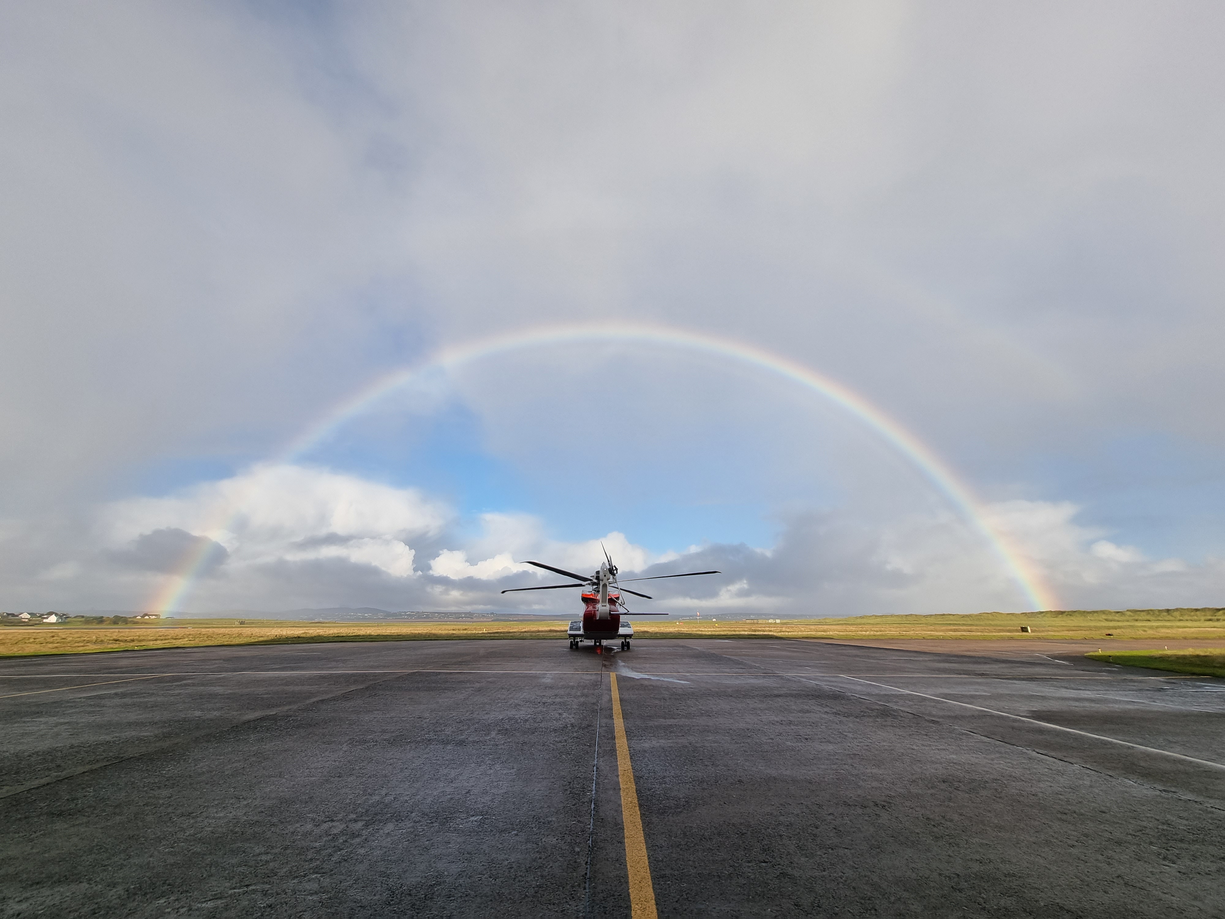 Rainbow over HM Coastguard helicopter on runway at Stornoway