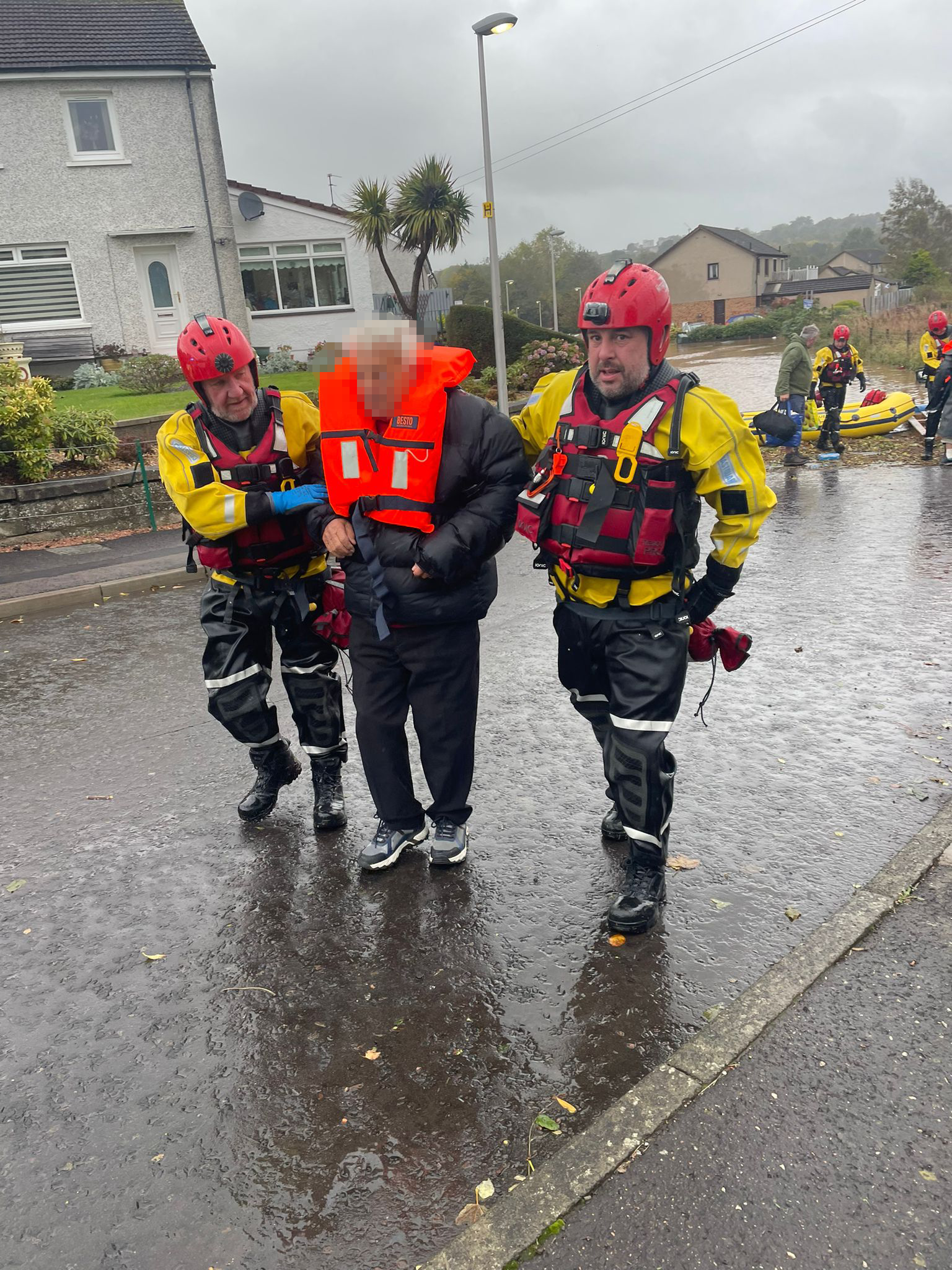 Two Coastguard officers help a person caught in Storm Babet floods