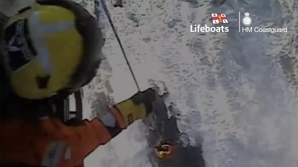 View from a HM Coastguard rescue helicopter. A winch operator assists a person in trouble in the water