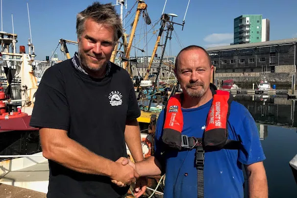 Sidney Rose vessel owner Ben and shakes hands with man overboard Paul. 