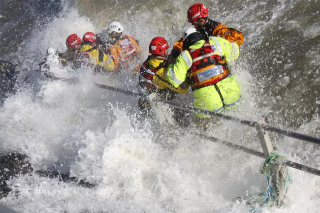 Coastguard rescue officers engulfed in sea spray as they practice practice a water rescue