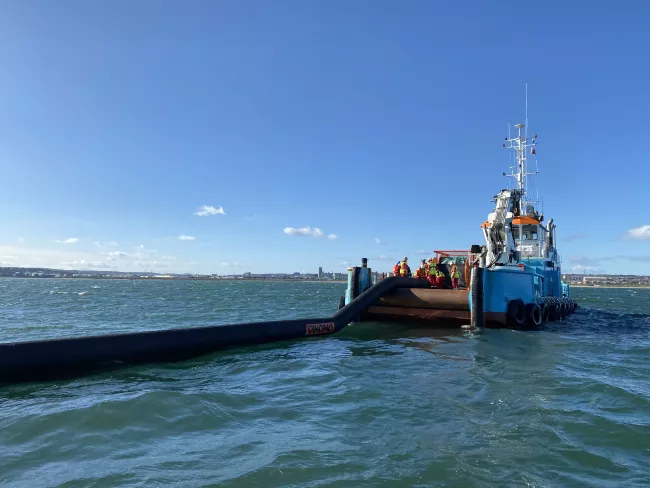 A counter-pollution boom is delivered from the back of a vessel in the sea off Aberdeen